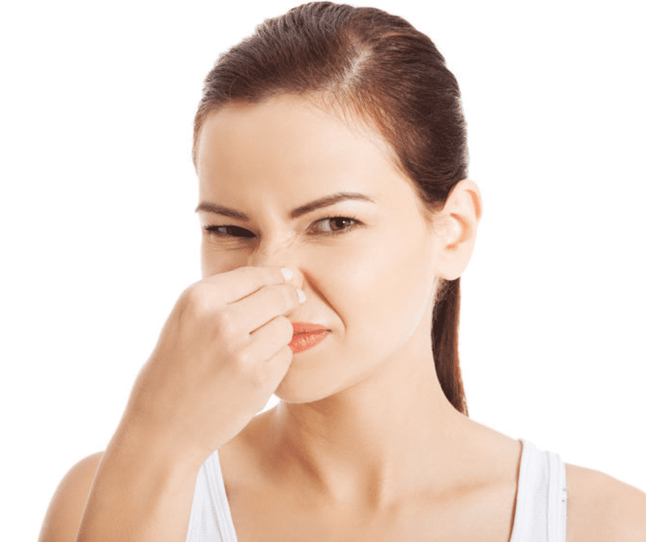woman pinching nose because of bad smell when turning on furnace