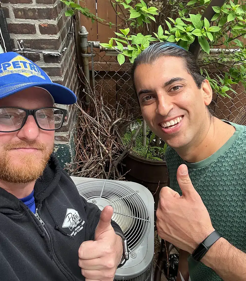 A Petri Technician with a happy customer next to an AC unit.