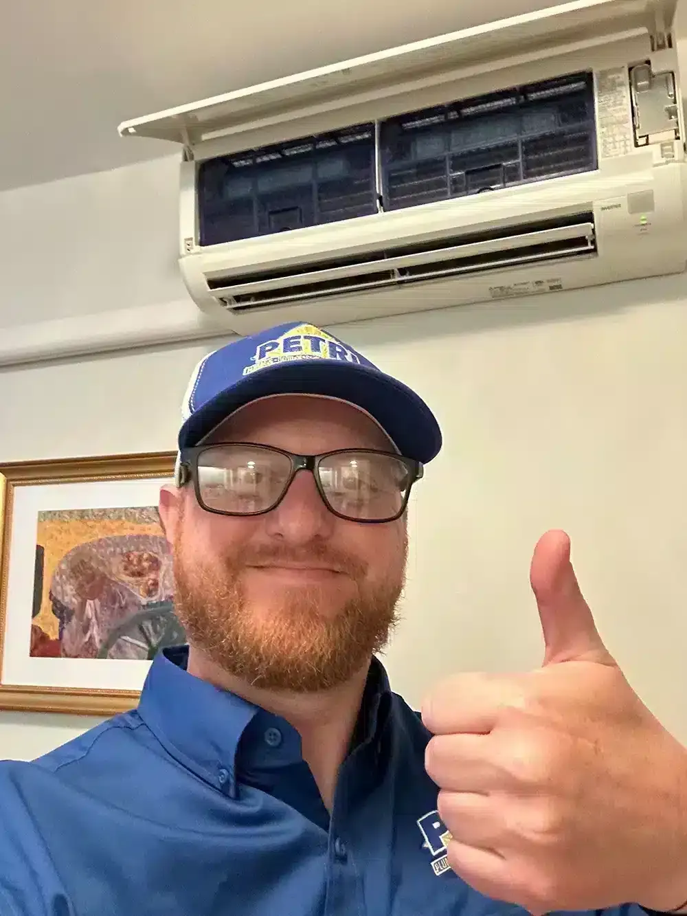 A Petri Technician smiling and giving a thumbs up after installing a new ductless HVAC unit in a Brooklyn, NY home.